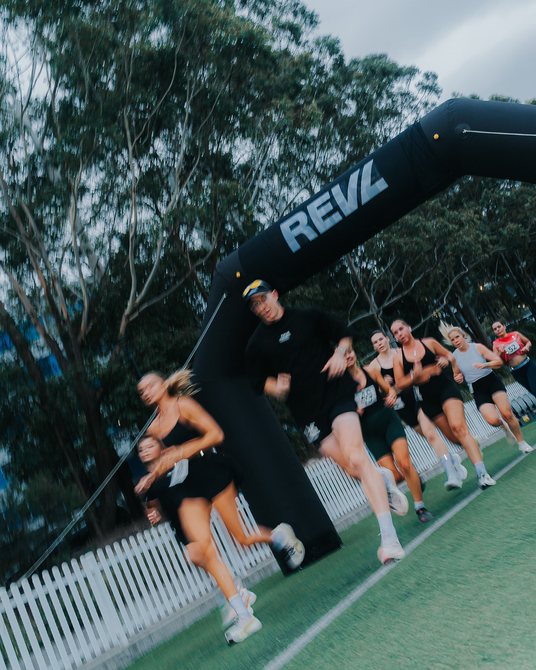 Runners through the REVL Training arch at a REVL PACE run